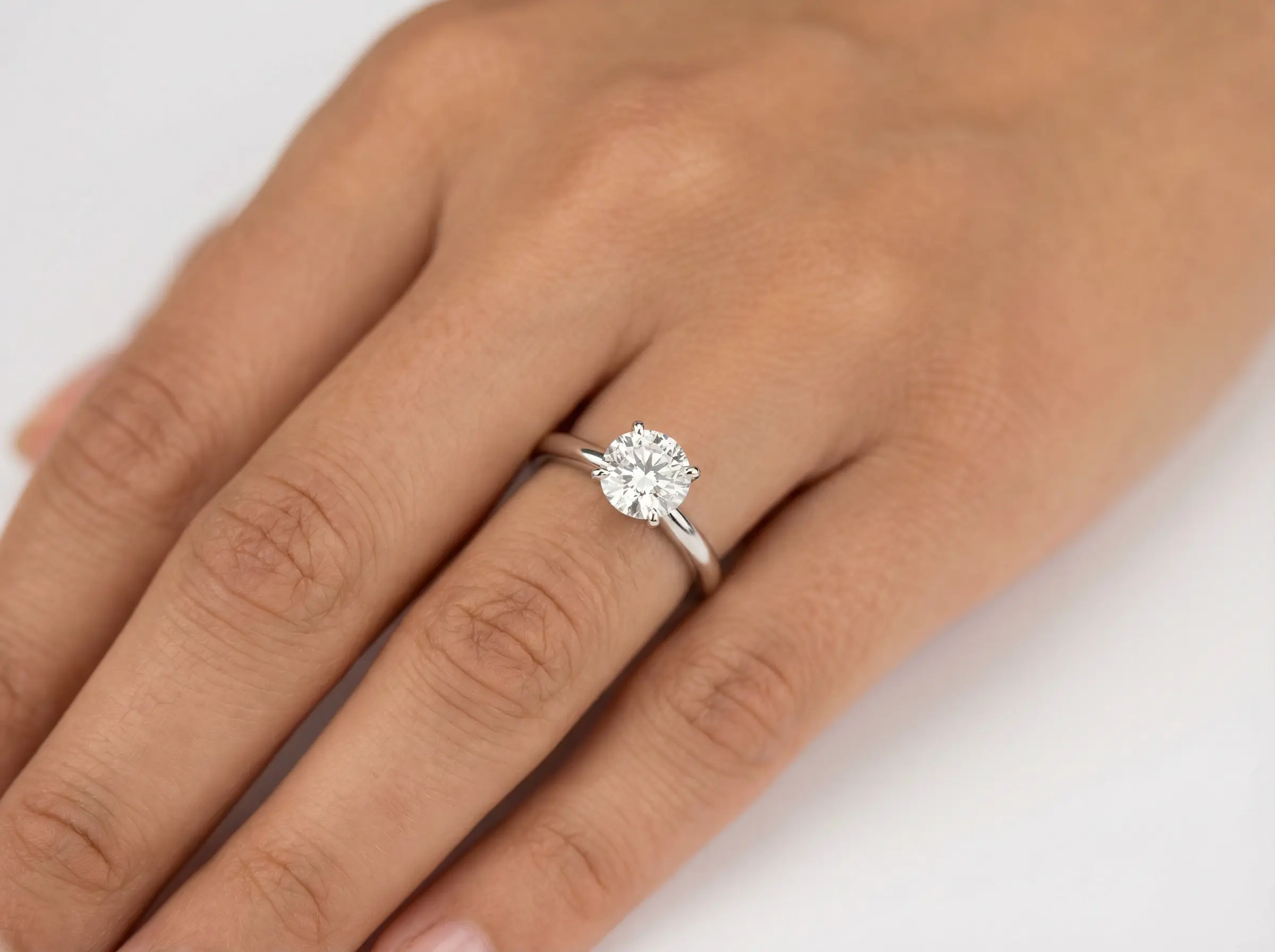 AI-generated hand model wearing a diamond engagement ring on white background
